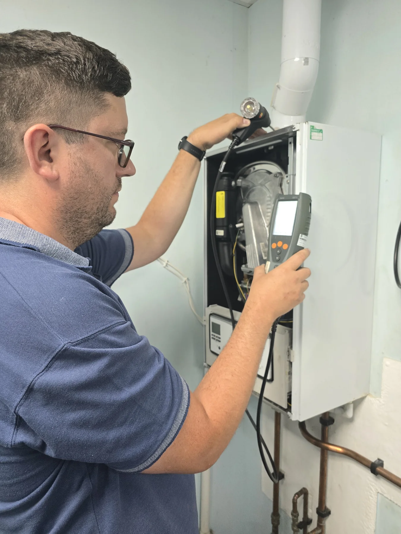 Engineer using a flue gas analyser on a boiler